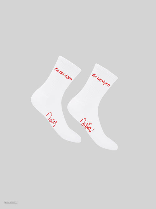 Paar weiße Tennissocken mit rotem Schriftzug „die nervigen“ am Schaft und den handschriftlichen Namen „Joey“ und „Julia“ am Fuß