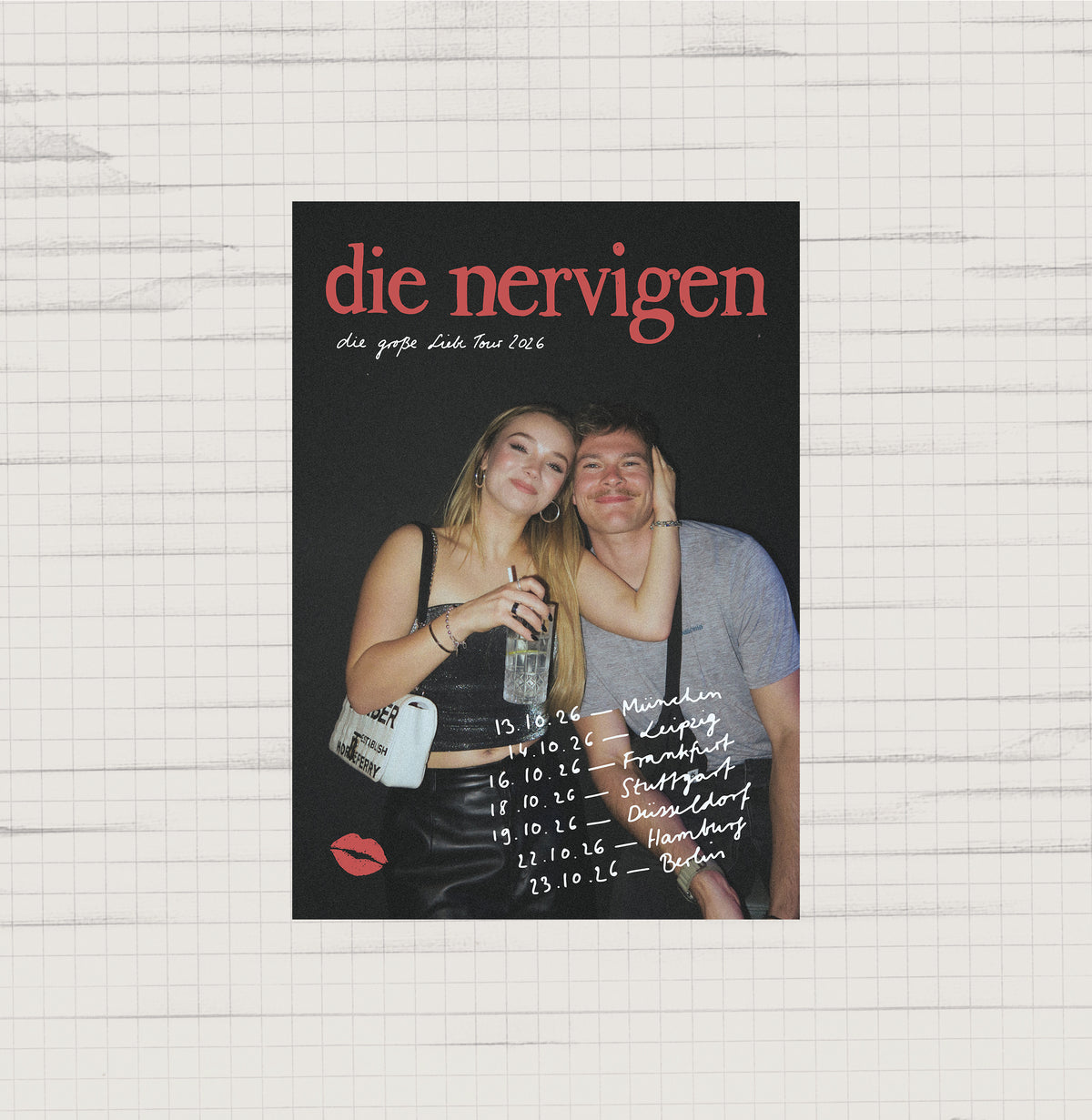 Tourposter „die nervigen – die große Liebe Tour 2026“ auf kariertem Papier: Foto einer blonden Frau und eines Mannes, die sich lächelnd umarmen, mit den Tourterminen München 13.10., Leipzig 14.10., Frankfurt 16.10., Stuttgart 18.10., Düsseldorf 19.10., Hamburg 22.10. und Berlin 23.10.